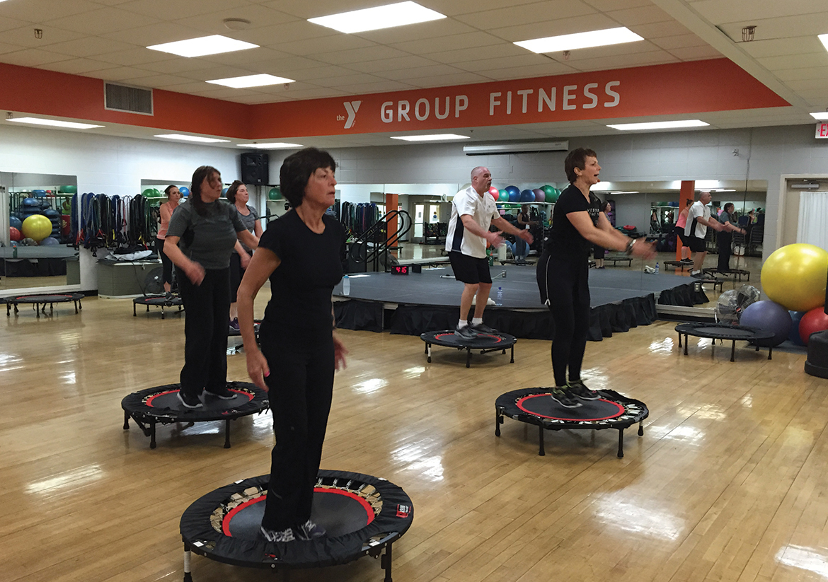 Group of adults exercising in a room with personal trampolines
