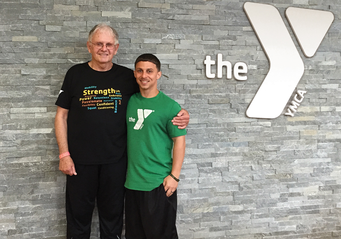 Older man and younger YMCA staff personal trainer smiling for a picture together
